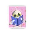 A square art print featuring a cartoon skeleton reading a blue book on a pink background with the words 'let me Read In Peace.' The print is shown centered against a light gray studio background.