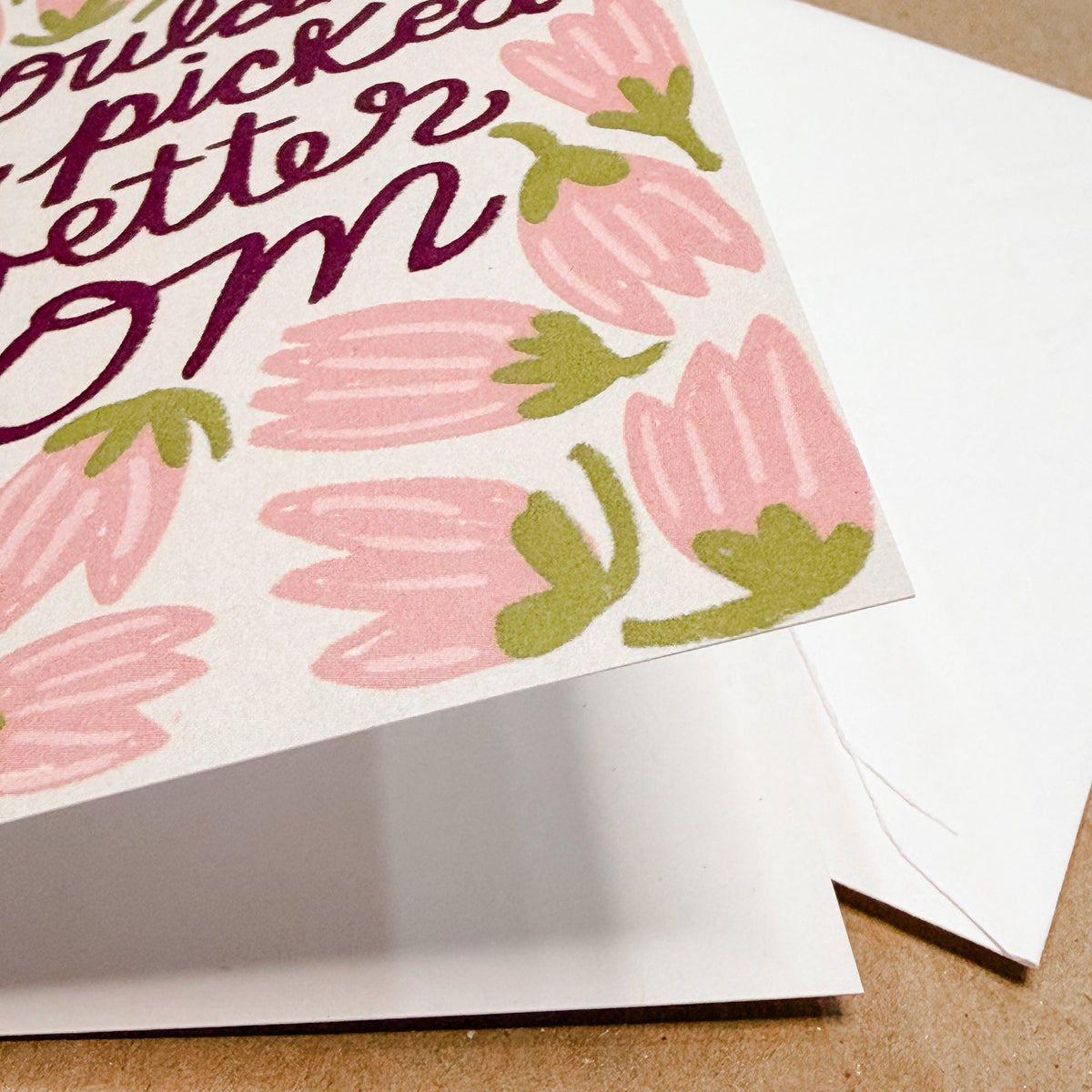 Greeting card with pink floral design and text on a brown surface