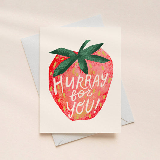Greeting card with strawberry design and 'Hurray for you!' text on a beige background