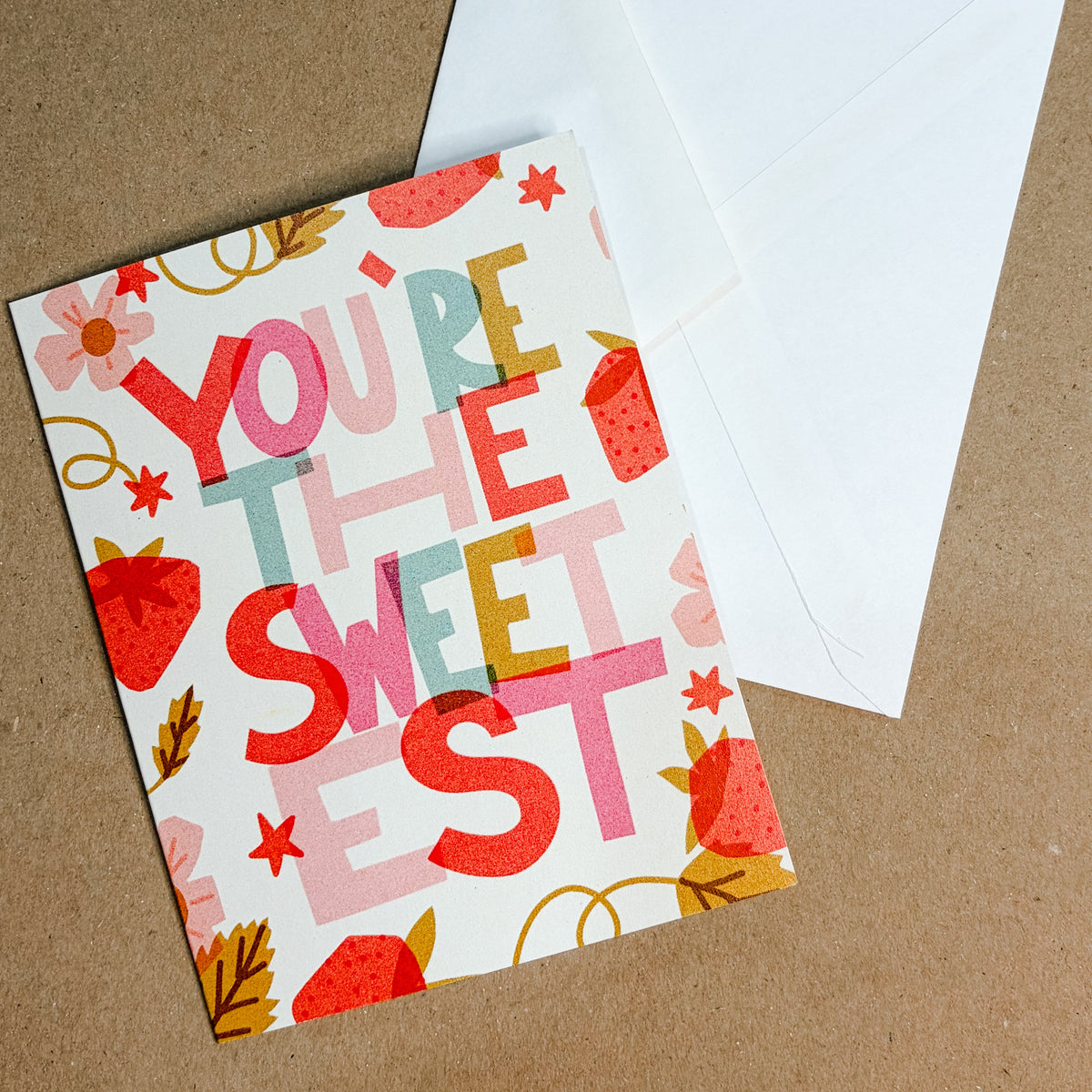 Greeting card with 'You're the Sweetest' text and a white envelope on a brown background