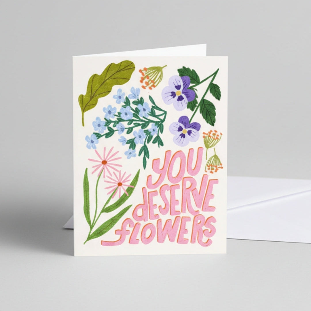 Greeting card with floral design and 'You deserve flowers' text on a gray background