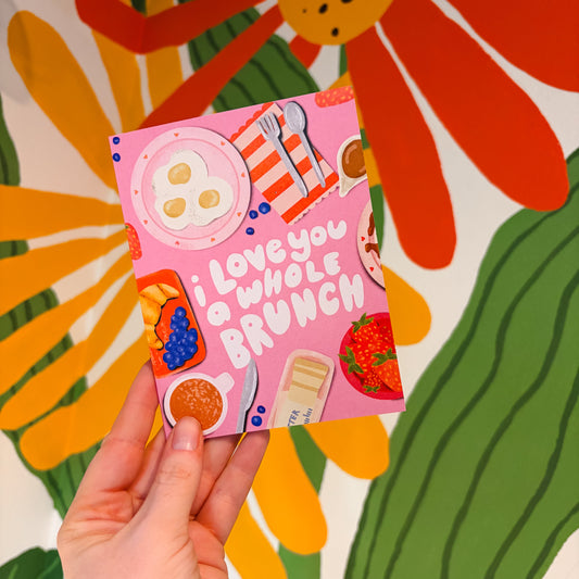 Hand holding a pink card with food illustrations against a colorful floral background