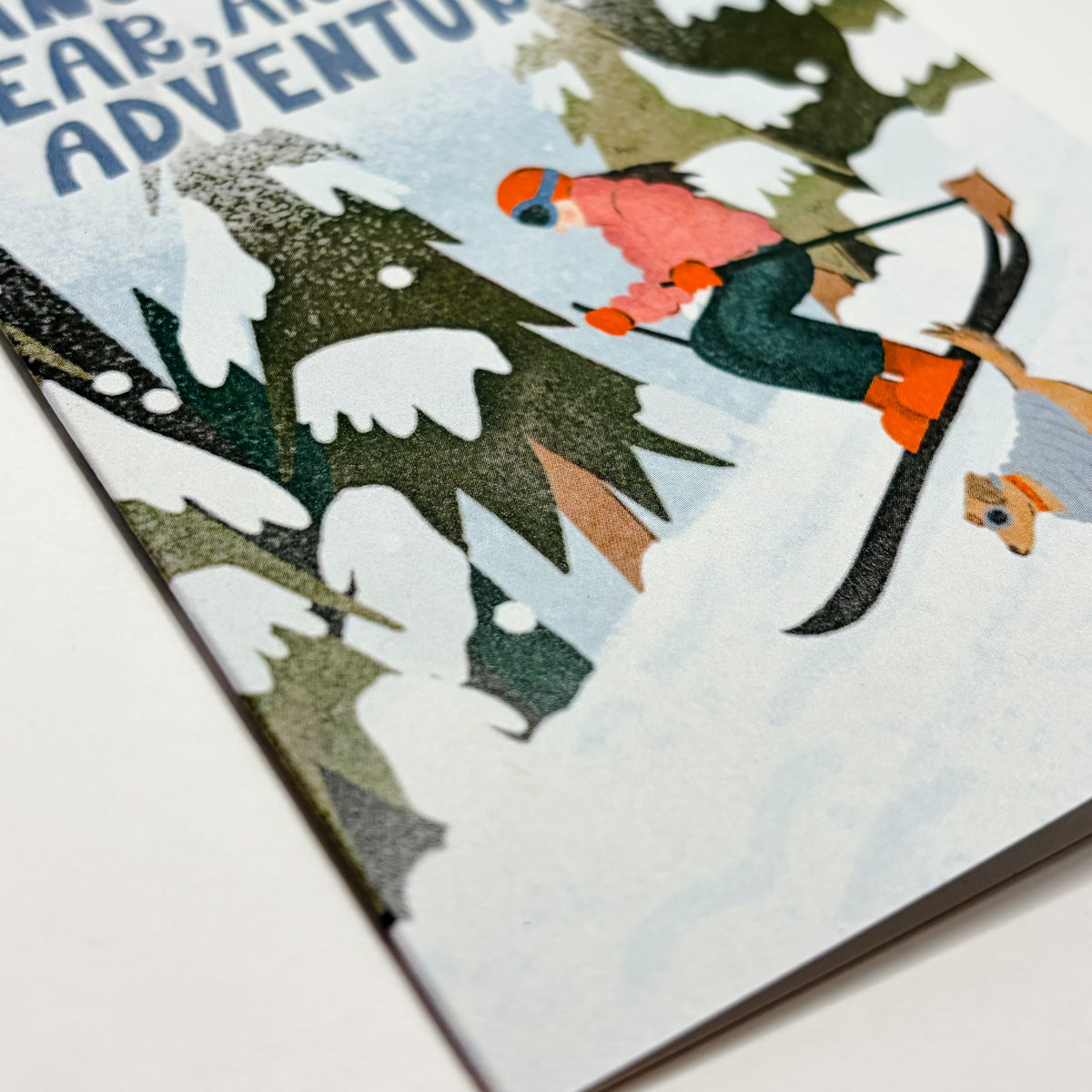 Card with illustration of a person skiing through a snowy landscape and text 'Another Year, Another Adventure'.